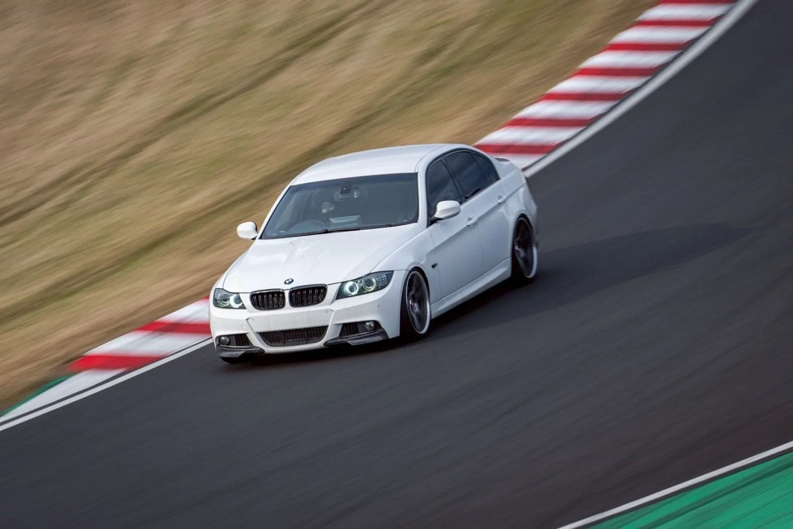 鈴鹿サーキットのコーナーを走る白いBMW E90
